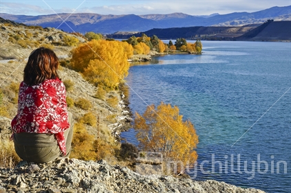 A woman sitting admiring the view of Lake Dunstan in autumn