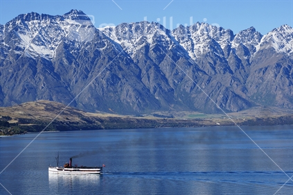 The Queenstown Ferry on the lake, with snow-capped mountains in the background