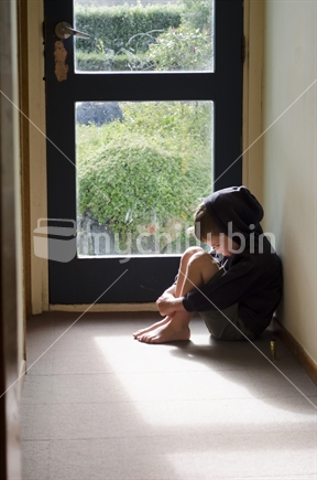 Young boy sitting in the hallway looking sad