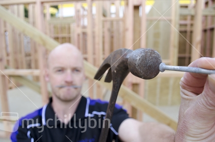 Man hammering a nail on a building site.