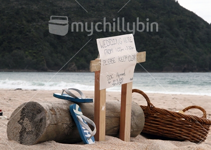 ''Wedding Here'' sign nailed to a rough sawn make shift wooden frame on the beach, Jandals welcome and bring a picnic basket. DOC approved. 