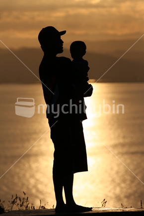Maori father and daughter silhouetted by Gisborne's setting sun