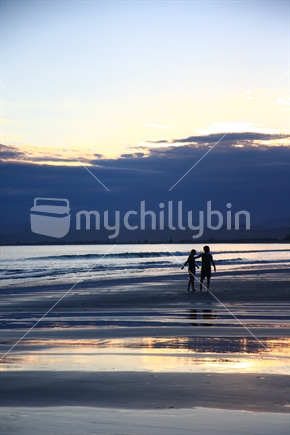 A couple walking along a Gisborne beach (high ISO)
