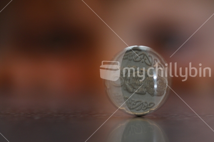 A boy watches a New Zealand 20 cent coin spin on a benchtop