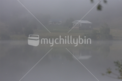 Farm cottage across a lake on a misty morning (High iso)
