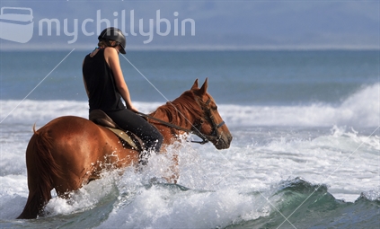 A young woman takes an afternoon ride in the surf at Raglan.