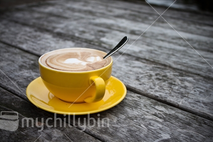 Cup and saucer of coffee on wooden table.