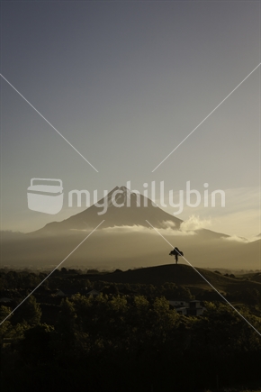Sunset view of Mount Taranaki with lone tree silouette in foreground.