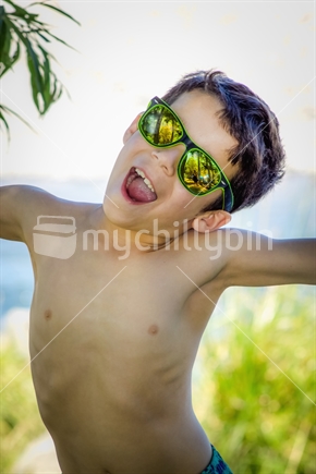 Close up image of a young kiwi kid outdoor in summer wearing sunglasses