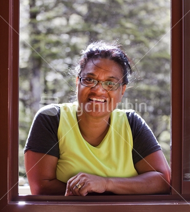 Middle-aged Polynesian lady smiles through window frame