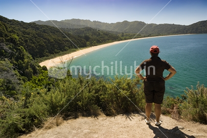 Middle aged woman looks out over Totaranui Beach, on the Great Walk at Abel Tasman National Park, South Island