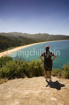 Middle aged woman looks out over Totaranui Beach, on the Great Walk at Abel Tasman National Park, South Island