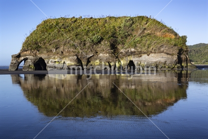 Elephant Rock reflected in wet sand on Tongaporutu Beach, Taranaki