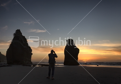 Three sisters rock stacks on Tongaporutu Beach at sundown with lone photographer