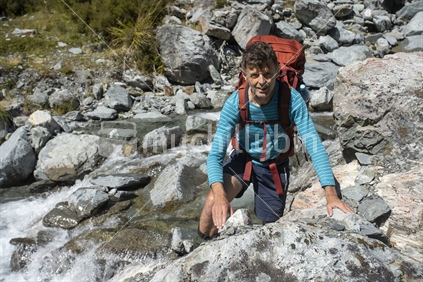 Male Kiwi tramper climbs out of stream, Nelson Lakes National Park