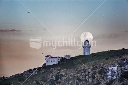 Full moon rise over Tairoa Head lighthouse on Otago Peninsula near Dunedin