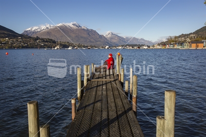 Red man on the end of a long jetty at Lake Wakatipu