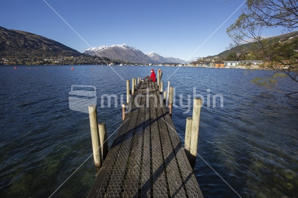 Red man on the end of a long jetty at Lake Wakatipu