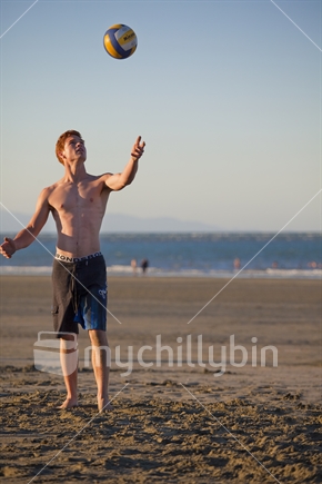 Teenage guy serves volleyball on Tahunanui Beach, Nelson