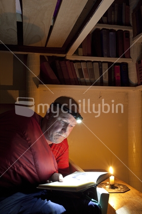 Man reads by torch and candlelight in mountain hut: closeup (High ISO image)