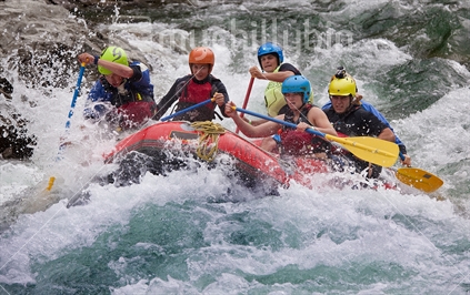 Team of competitors in a rubber raft tackle whitewater on the Buller River