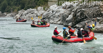 Trio of red rafts float lazily down the Buller River gorge; with a person going overboard.