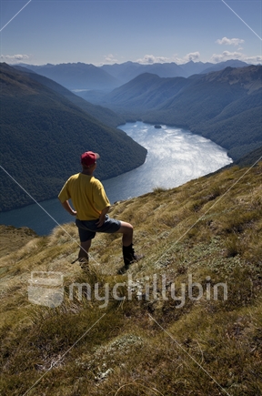 Yellow & red hiker gazes out onto Lake Christabel, Lewis Pass National Reserve