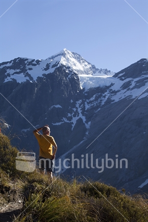 Tramper admires the Breakaway Glacier tumbling off Mt Aspiring into the shadows of Matukituki Valley.