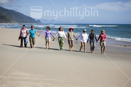 8 ladies walk deserted sandy beach on Heaphy Track, Kahurangi National Park