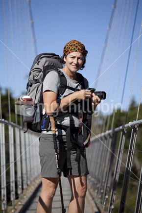 Middle-aged female tramper on swingbridge across Heaphy River, Kahurangi National Park