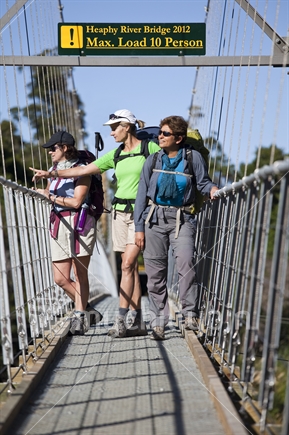 Tramping trio of middle-aged women on bridge. Heaphy Track, Kahurangi National Park