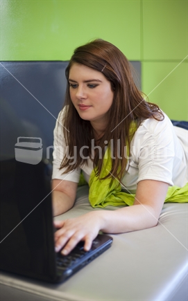 Young brunette student using laptop computer.