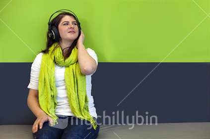 Young woman in jeans listens to music on headphones
