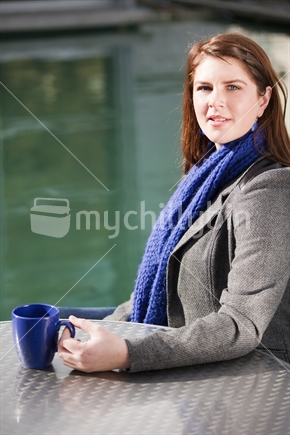 Young brunette girl in blue scarf with coffee mug