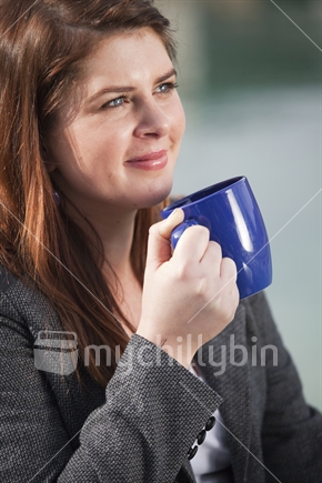 Girl in grey coat with coffee cup at cafe