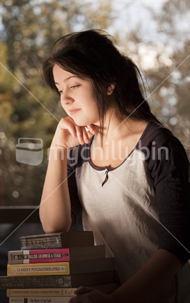 Teenage student leans on stack of study books