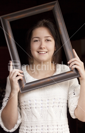 Portrait of teenage girl smiling through picture frame
