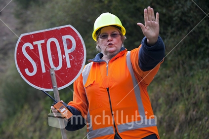Female traffic controller on rural road with large STOP sign