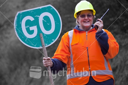 Go Girl - Woman traffic controller on forestry road with large GO sign and radio