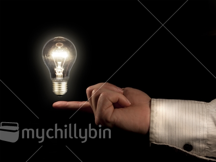 Floating an idea - an illuminated light bulb hovers above a business man's finger