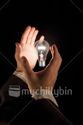 Light handed. Playing with an idea - an illuminated light bulb hovers above a business man''s hands