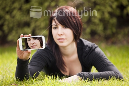 Brunette young woman takes self-portrait with mobile phone