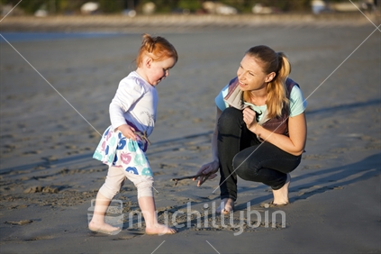 Young Kiwi mum, with small daughter on beach