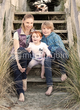Young mother with young children pose on beach-side staircase