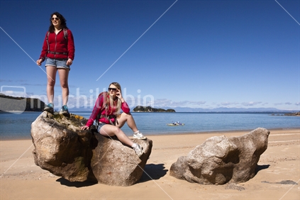 Two female friends relax at Stillwell Bay in the popular Abel Tasman National Park. 