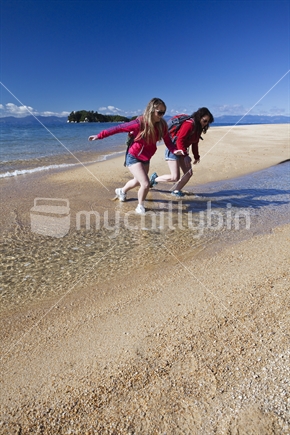 A pair of young female friends get wet feet at Appletree Bay in Abel Tasman National Park.