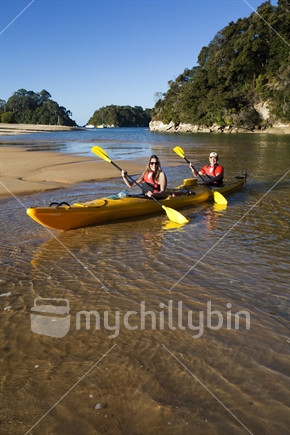 Couple in kayak navigate up the lagoon at Kaiteriteri Beach, gateway to Abel Tasman National Park.