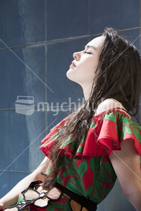 Attractive young Polynesian teenager relaxes by falling water of fountain. Wearing a traditional tapa cloth piece 