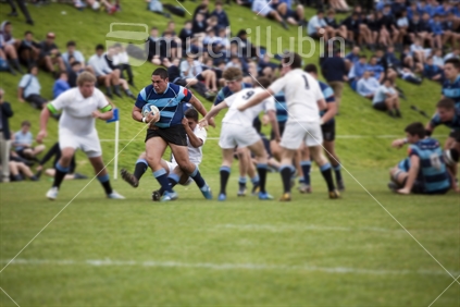 Teenage boy breaks tackle in annual rugby tournament at Nelson College, the home of New Zealand rugby tradition. Focus, player with ball only.