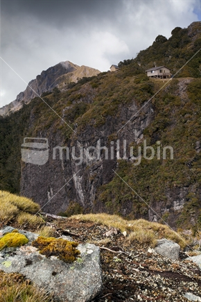 A high bluff, with Ghost Lake Huts perched atop. Viewed from the Old Ghost Road cycle trail, Buller district, West Coast